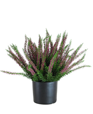 La Plante Artificielle Erica 33 cm est une plante artificielle dressée dans un pot noir, avec des feuilles vertes touffues et de nombreuses longues tiges décorées de petites fleurs violettes et roses qui s'étalent vers l'extérieur.