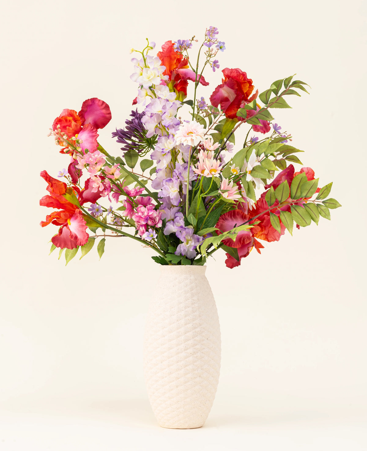 Le bouquet de fleurs artificielles en soie Pink Pop est présenté dans un vase à structure blanche, avec des fleurs artificielles roses vives et des feuilles vertes sur un fond clair.