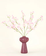 Le bouquet de fleurs artificielles en soie Pois rose clair, avec plusieurs tiges de pois rose clair dans un vase bordeaux côtelé, se dresse sur un fond pâle - idéal pour tout intérieur de fleurs artificielles.