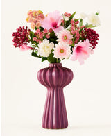 Un bouquet de fleurs artificielles de Zijden, « Bloom & Berry », avec des fleurs artificielles roses, blanches et rouges, est magnifiquement disposé dans un grand vase violet nervuré sur un fond blanc uni.