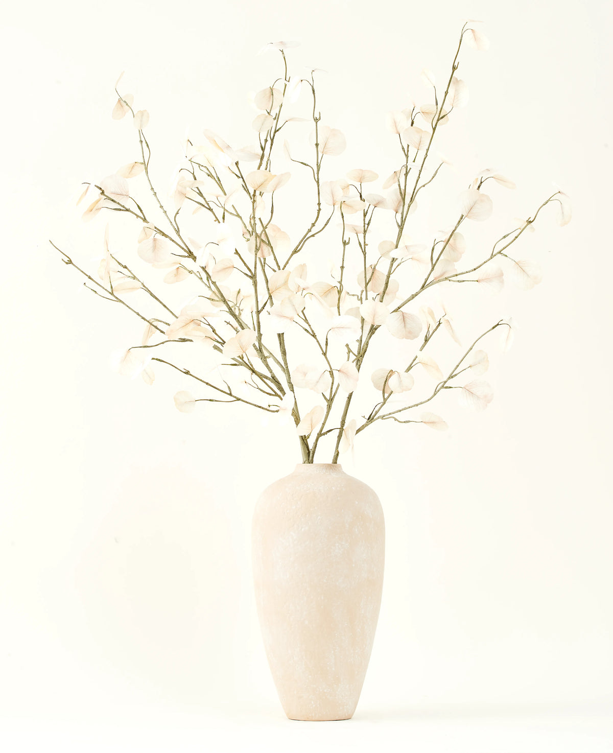 Le bouquet de fleurs artificielles en soie crème d'eucalyptus dans un grand vase en céramique beige clair avec des feuilles blanches transparentes crée une atmosphère sereine dans tout intérieur de fleurs artificielles sur un fond clair.