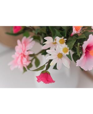 Un gros plan de la fleur artificielle Margriet 60 cm blanc/rose montre des marguerites roses et blanches avec un cœur jaune dans un vase blanc sur un fond neutre.