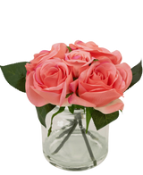 Le bouquet de roses artificielles Real Touch Pink 18 cm contient de petites roses artificielles roses avec des feuilles vertes dans un pot en verre transparent sur un fond blanc.