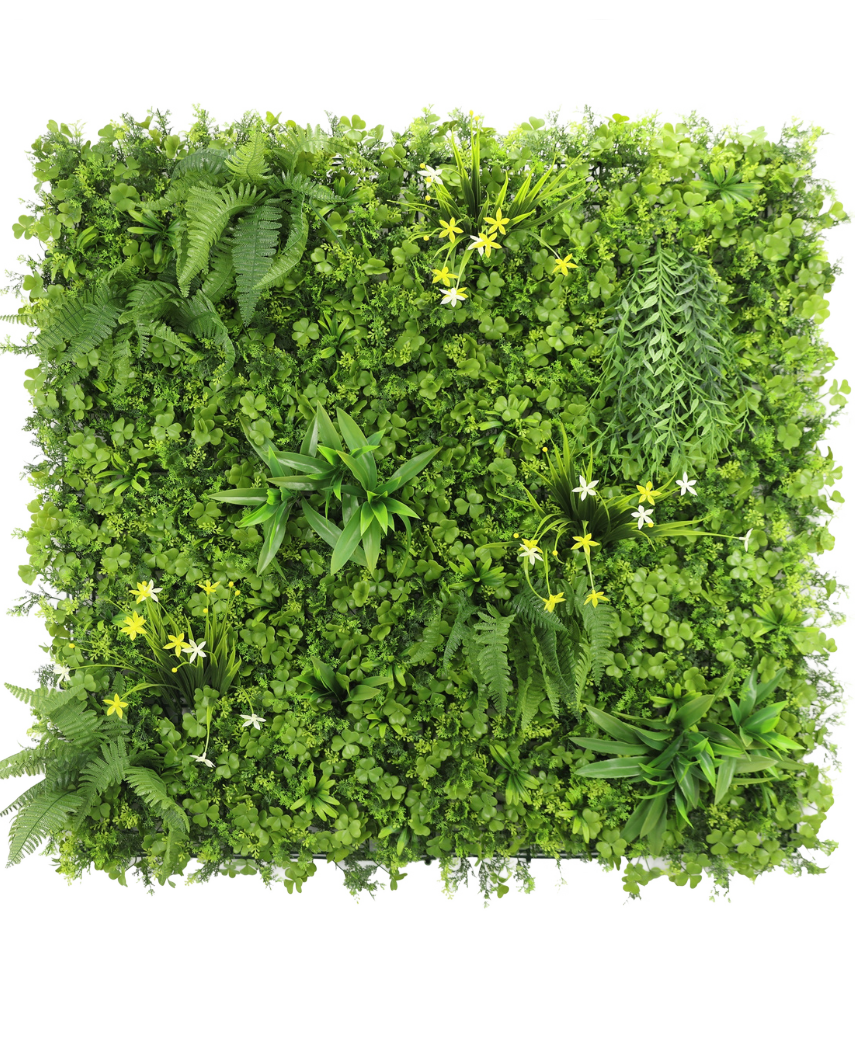 La Haie Artificielle Jonquille Smile 100x100 cm UV est un mur végétal vertical carré au feuillage vert dense, des fougères et des petites fleurs jaunes et blanches, sur un fond blanc vu de dessus.
