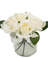 Le Bouquet de Roses Artificielles Real Touch Blanc 18 cm est un petit vase en verre transparent avec des roses blanches réalistes et des feuilles vertes, sur un fond blanc uni.