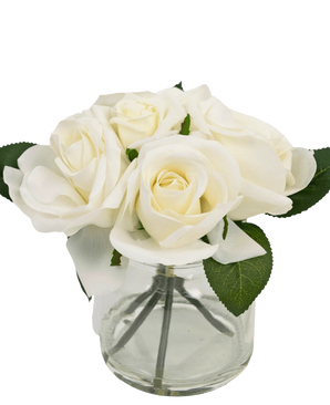 Le Bouquet de Roses Artificielles Real Touch Blanc 18 cm est un petit vase en verre transparent avec des roses blanches réalistes et des feuilles vertes, sur un fond blanc uni.