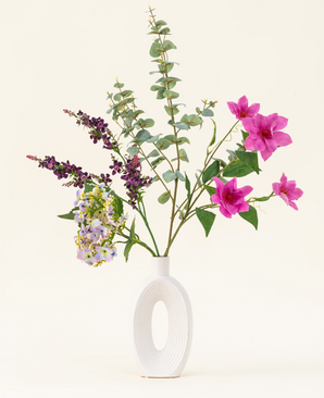 Disposé dans un vase blanc moderne, le bouquet de fleurs artificielles en soie Lavender Skies présente des fleurs artificielles roses et violettes, des accents jaunes et un feuillage vert luxuriant – magnifique sur un fond clair uni.