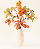 Le bouquet de fleurs artificielles en soie Autumn Flair comprend un vase avec une structure blanche et une branche de lanterne, des fleurs orange en forme de lanterne et des feuilles vert-rouge, qui forment un décor automnal élégant sur un fond clair et uni.
