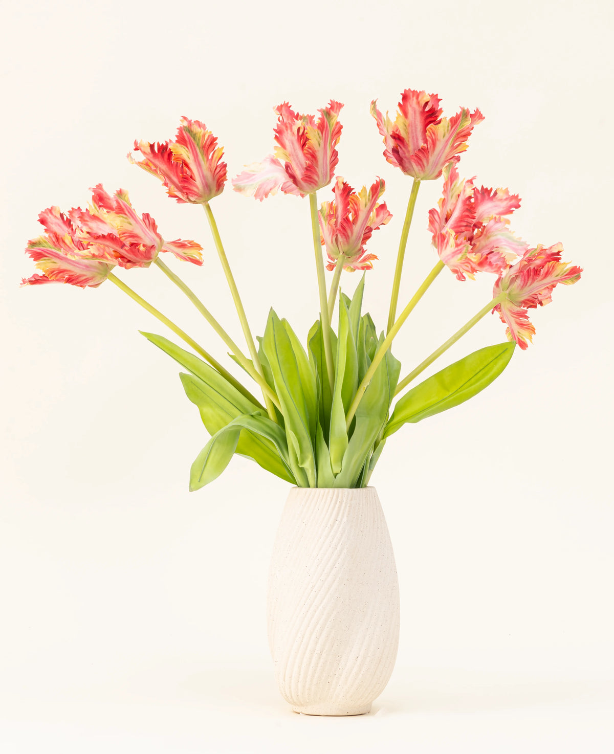 Un vase avec une structure blanche montre le bouquet de fleurs artificielles en soie French Perakeet Tulip rouge/jaune, avec des tulipes rouges et jaunes réalistes avec des feuilles vertes sur un fond clair uni.
