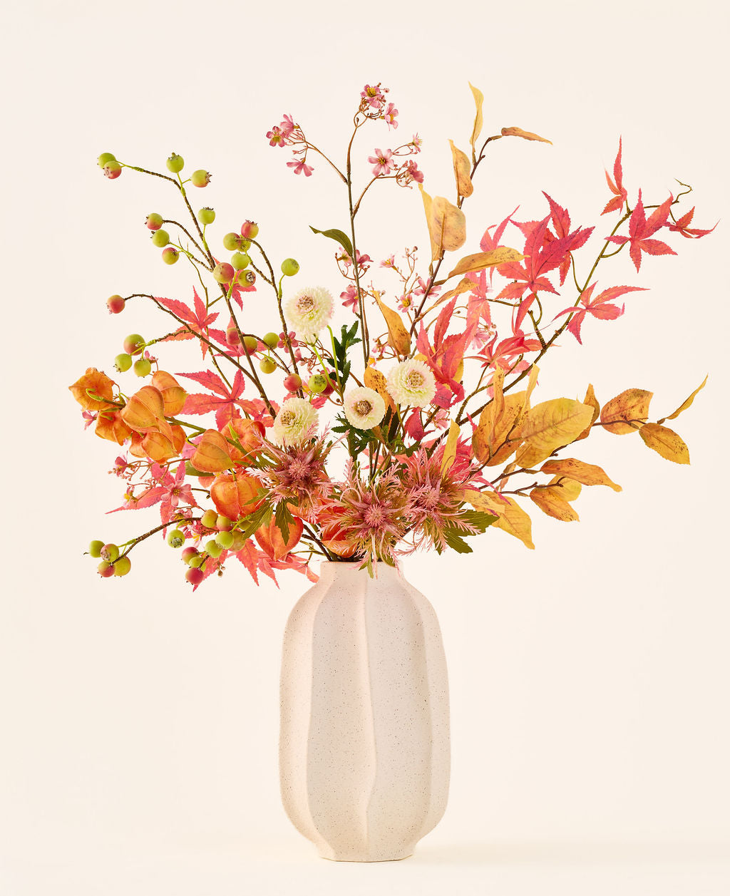 Bouquet de fleurs artificielles en soie 'Autumn Breeze' dans un vase en céramique blanche, avec un arrangement de feuilles d'automne, de petites baies vertes, de fleurs roses et de fleurs blanches, composé de fleurs en soie de haute qualité. Placé sur un fond clair – le bouquet de fleurs artificielles parfait pour donner à n’importe quelle pièce une atmosphère saisonnière durable.