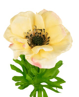 L'Anémone artificielle Real Touch jaune 52 cm a des pétales jaune clair doux, un cœur sombre avec des étamines noires et des sépales à feuilles vertes, sur un fond blanc.
