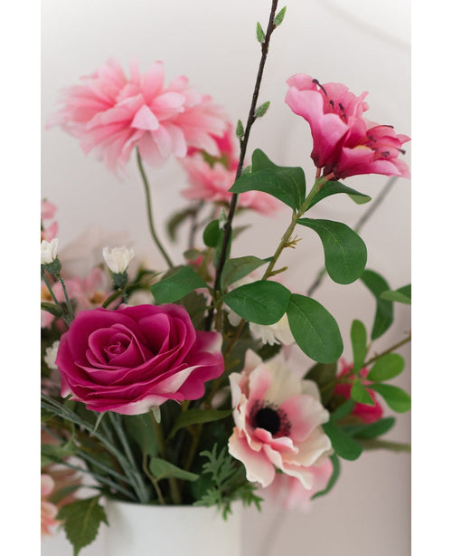 Gros plan de la Rose Artificielle Real Touch 56 cm rose, un bouquet de roses artificielles roses aux feuilles vertes dans un vase blanc, sur fond clair.