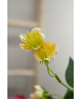 Gros plan de la fleur artificielle renoncule 77 cm en jaune et blanc, avec des tiges et des feuilles vertes sur un fond flou - idéale pour tous ceux qui souhaitent créer un bouquet avec de belles fleurs artificielles.