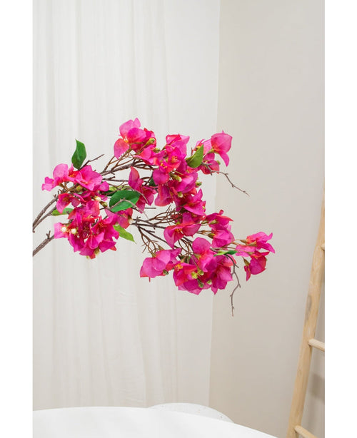 La fleur artificielle Bougainvillier 90 cm violet, avec des fleurs violettes vibrantes et des feuilles vertes, est présentée sur un fond neutre clair à côté d'une échelle en bois à droite.