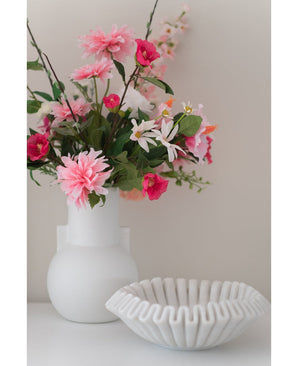 Un vase blanc avec une fleur artificielle Rhododendron Azalea 73 cm fuchsia se trouve à côté d'un bol blanc en céramique nervurée sur une surface unie sur un fond neutre.