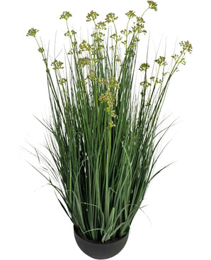Le pot de gazon artificiel, fleur de poireau, oignon, ignifuge de 100 cm a de longues feuilles minces ressemblant à de l'herbe verte et de petites grappes de fleurs jaune-vert dans un pot rond noir, sur un fond blanc.