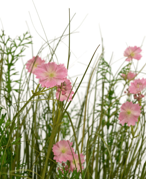 Le pot d'herbe d'oignon de fleur de Gesang rose de gazon artificiel 90 cm ignifuge a des fleurs roses avec un cœur vert clair qui fleurissent parmi des herbes hautes et fines et des plantes à feuillage luxuriant, le tout sur un fond blanc.