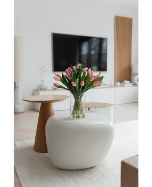 Un salon moderne avec un tapis blanc, une grande table basse ovale et une petite table d'appoint ronde en bois. Sur la table se trouve le bouquet artificiel en soie Tulipes dans un vase Rose ; une télévision et une décoration minimaliste complètent le décor.
