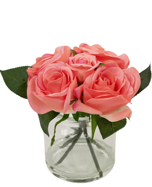Le bouquet de roses artificielles Real Touch Pink 18 cm contient de petites roses artificielles roses avec des feuilles vertes dans un pot en verre transparent sur un fond blanc.