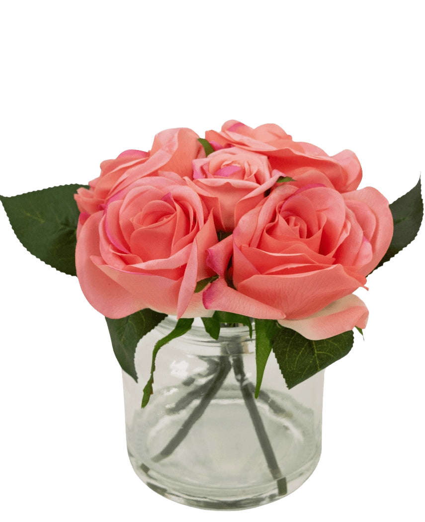 Le bouquet de roses artificielles Real Touch Pink 18 cm contient de petites roses artificielles roses avec des feuilles vertes dans un pot en verre transparent sur un fond blanc.