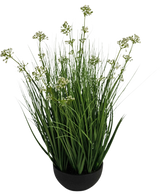 Le gazon artificiel poireau fleur oignon herbe pot 60 cm ignifuge a de hautes et fines feuilles vertes ressemblant à de l'herbe avec de petites grappes de fleurs blanches dans un pot noir, sur un fond blanc.